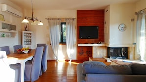 Una sala de estar con chimenea, televisor y comedor con sillas y una mesa.