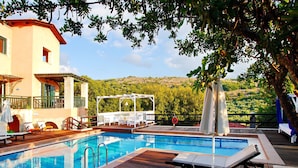 Un área de piscina con sillones de descanso y una pérgola.