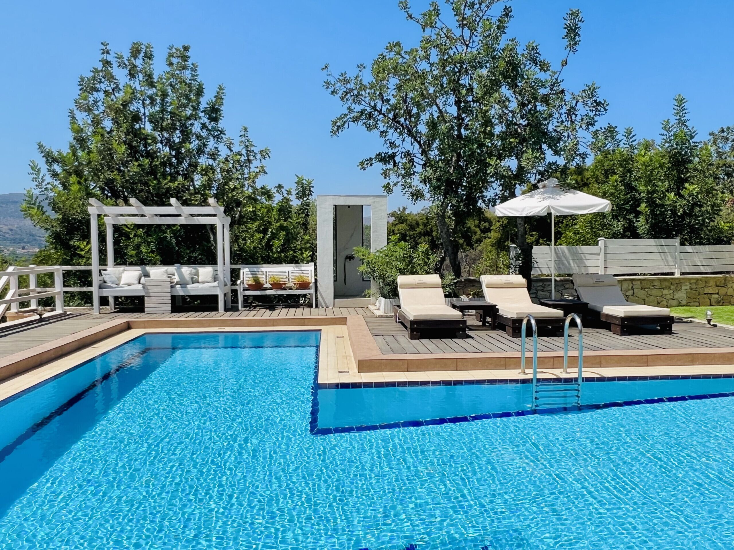 A swimming pool with lounge chairs and a pergola.