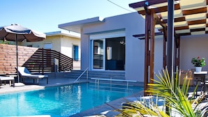 A pool area with lounge chairs, a wooden pergola, and a staircase leading to an upper level. - Villa Andreas (Tavronitis)