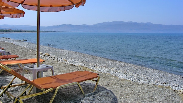 A beach with pebbles, a clear blue sea, and mountains in the distance. - Villa Andreas (Tavronitis)