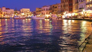 Une zone riveraine où sont amarrés des bateaux, des immeubles dotés de balcons et une rue animée où l’on croise de nombreuses personnes.