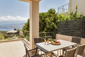 A balcony with a table set for two, two glasses of orange juice, and a bowl of fruit. - Villa Anemi (Sternes)