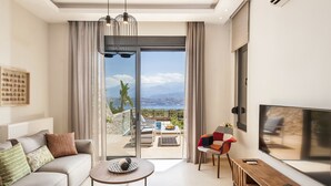 Un salon moderne avec un canapé, une table basse et un téléviseur. Il y a un balcon avec vue sur les montagnes.