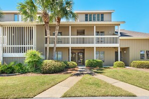 A two-story building with a balcony, a front door, and a small garden with a palm tree. - ✨Walk2Beach-Lake Front-5 Pools-Pet Friendly-2 Screened Porches-3BR Family Tides✨ (Miramar Beach)