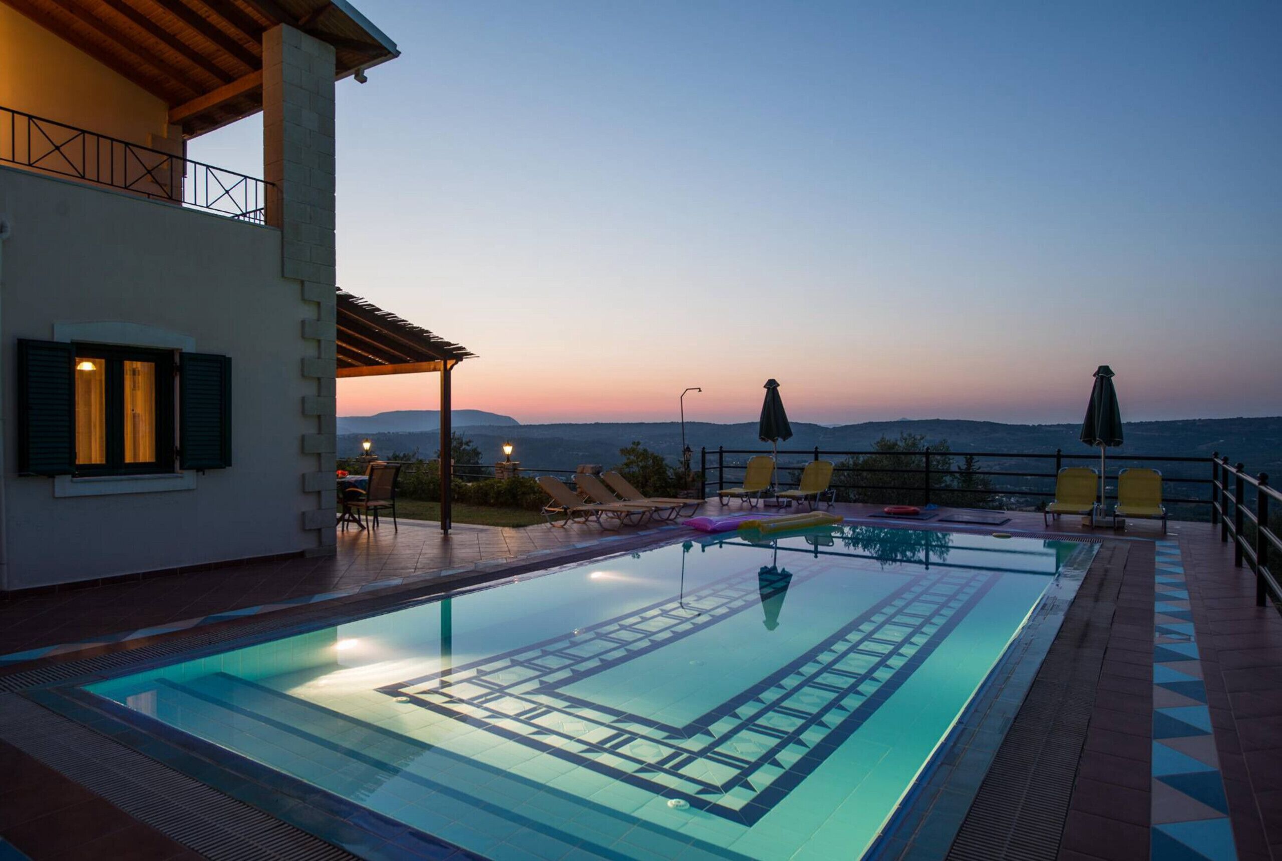 A swimming pool with a view of the mountains at dusk.