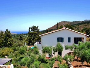 A single-story building with a flat roof, surrounded by greenery and a hilly landscape. - Villa Artemis (Vrises)