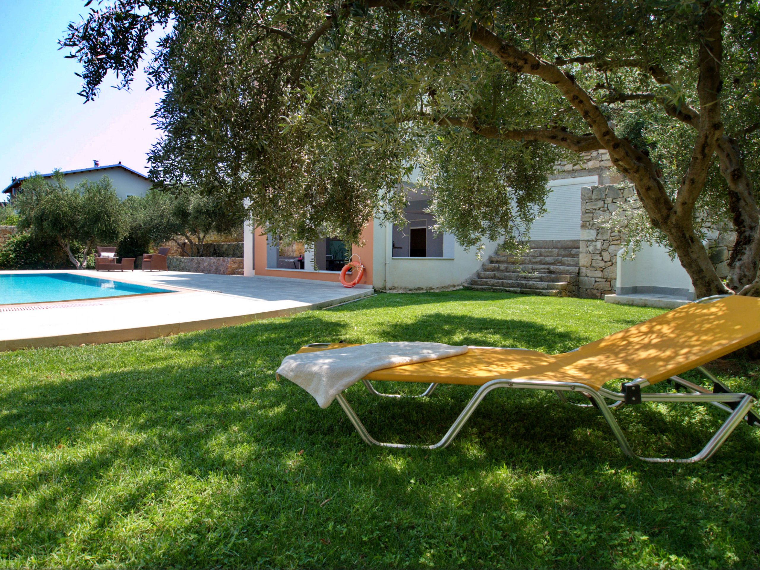 A poolside area with a lounge chair, a small pool, and a stone staircase leading to a building.