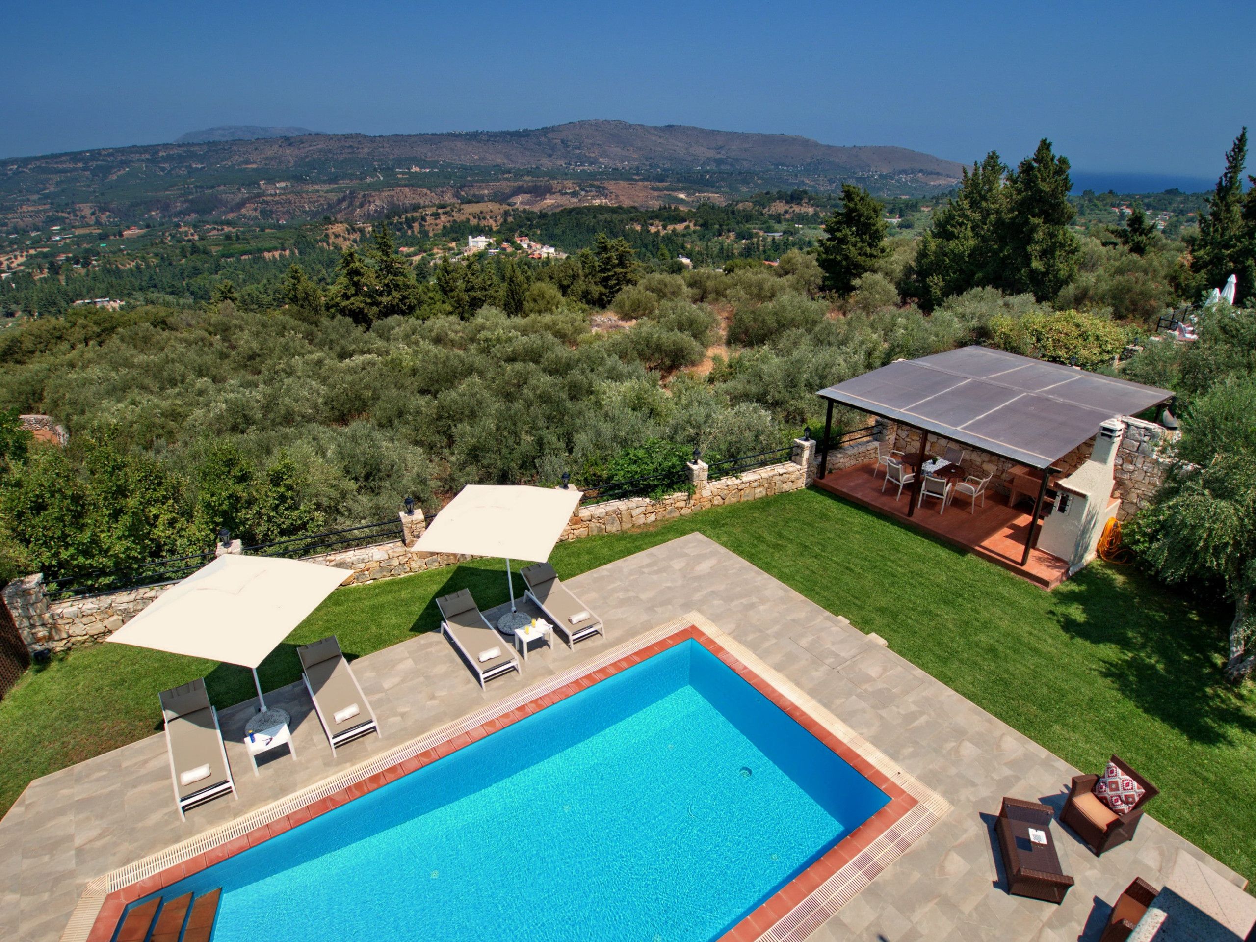 Una piscina con lettini, una veranda coperta e vista sul paesaggio circostante.