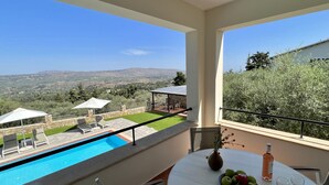 Ein Balkon mit Pool, Sitzgelegenheit im Freien und einem Tisch mit Obst und Weingläsern.