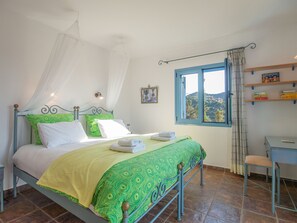 A bed with a canopy, a desk, a chair, and a window with a view of a hill. - Villa Clio (Stalos)