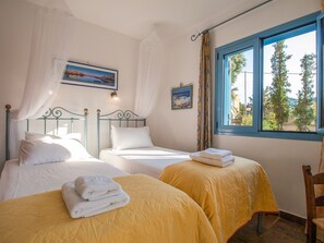 Quarto com duas camas, janela com vista para árvores e um quadro na parede.