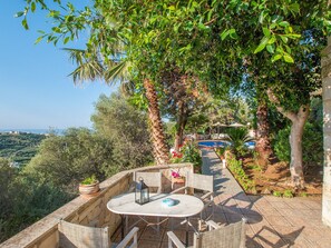 A patio with a table and chairs, a pool, and a view of the landscape. - Villa Clio (Stalos)