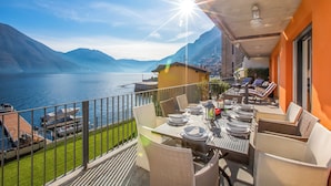 An outdoor dining area with a table set for four, overlooking a lake and mountains. - Argegno Fronte Lago (Argegno)