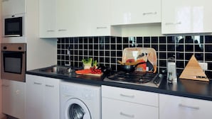 A modern kitchen with white cabinets, a built-in oven, microwave, and dishwasher. - Villa Isella - Mansarda (Carlazzo)
