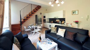 A living room with a sofa, a coffee table, and a dining area with chairs and a table. - Villa Isella - Mansarda (Carlazzo)