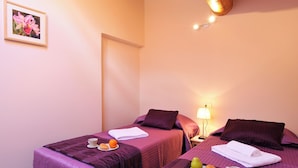A hotel room with two beds, each with purple bedding, a bedside table with a lamp, and a framed picture on the wall. - Villa Isella - Mansarda (Carlazzo)