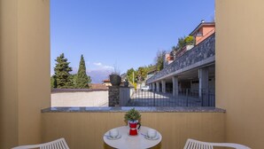 A balcony with two white chairs, a small round table, and a potted plant. - Fontana Del Lago Apt. 16 (Varenna)
