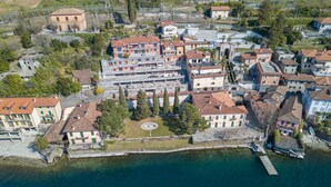An aerial view of a coastal town with buildings along the waterfront, a central plaza, and a dock. - Fontana Del Lago Apt. 16 (Varenna)