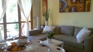 A living room with a sofa, a dining table with plates and a bowl of fruit, and a painting on the wall. - Alla Vigna Panoramica (Perledo)
