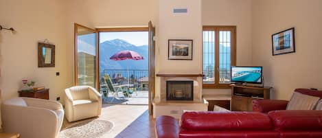 Una sala de estar con chimenea, televisor y un sofá rojo.