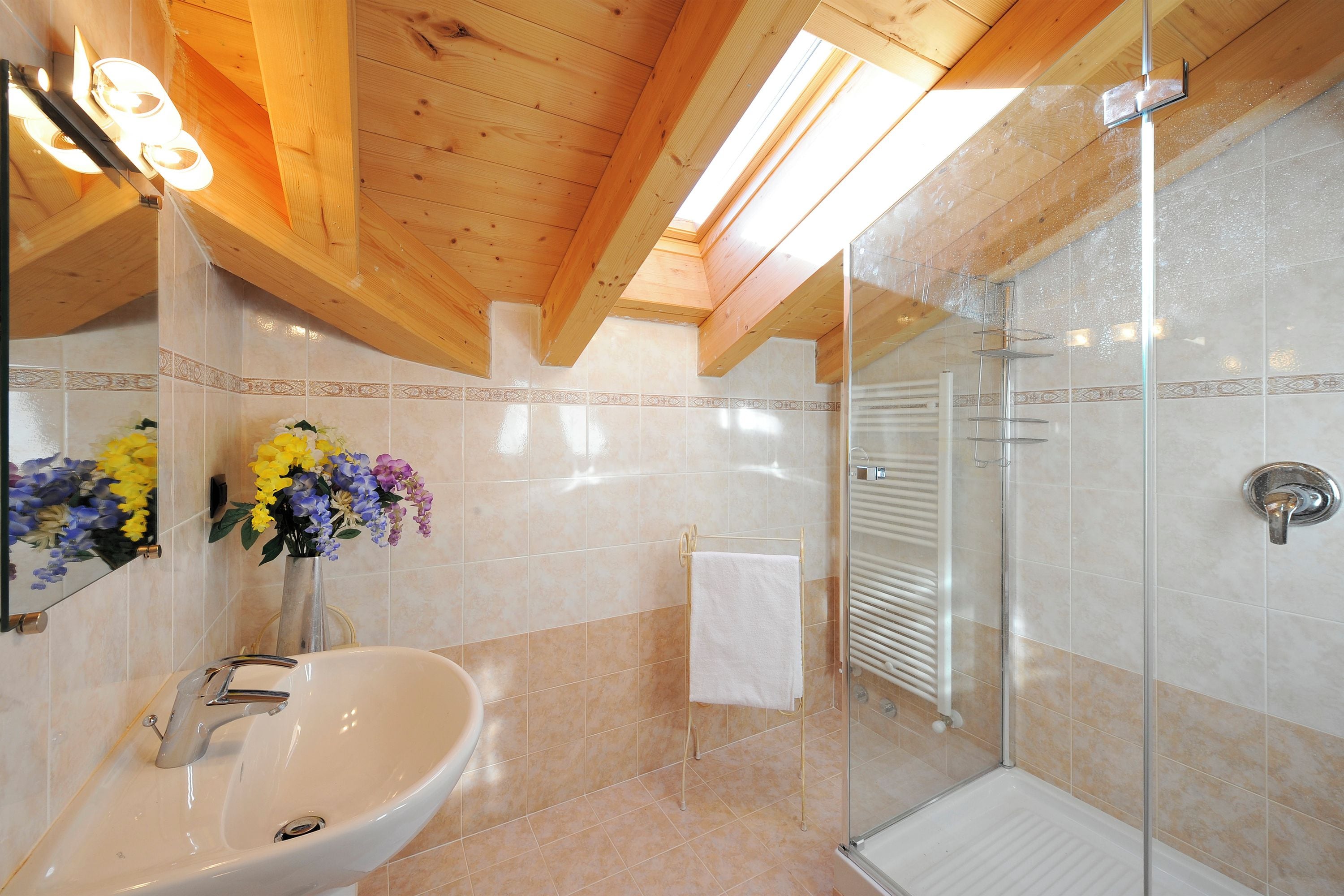 A bathroom with a sink, mirror, shower, and a towel rack.