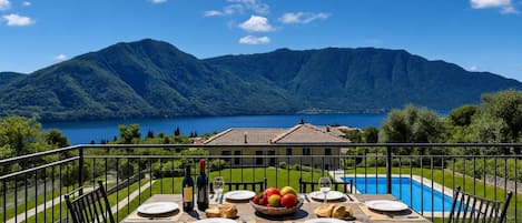 A dining table set outdoors with a mountain view and a swimming pool in the background.