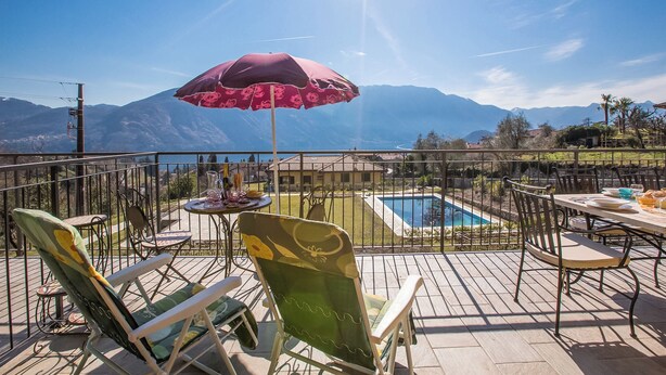 A deck with outdoor furniture, a pool, and a mountain view.