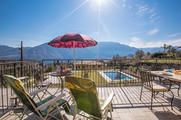 Terraza con mobiliario exterior, piscina y vista a la montaña.