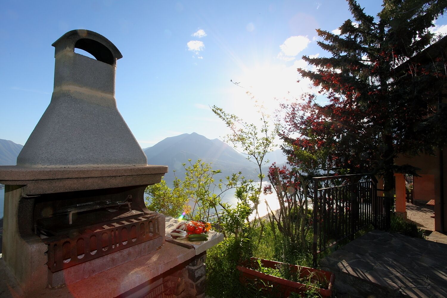 A stone barbecue grill with a view of mountains and a lake.