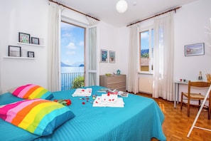 Un dormitorio con cama, una silla, una mesita y vista al mar.