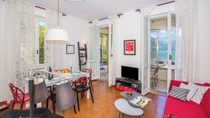Un coin repas avec une table, des chaises et un téléviseur. On y trouve également un canapé rouge et une fenêtre donnant sur un beau paysage.