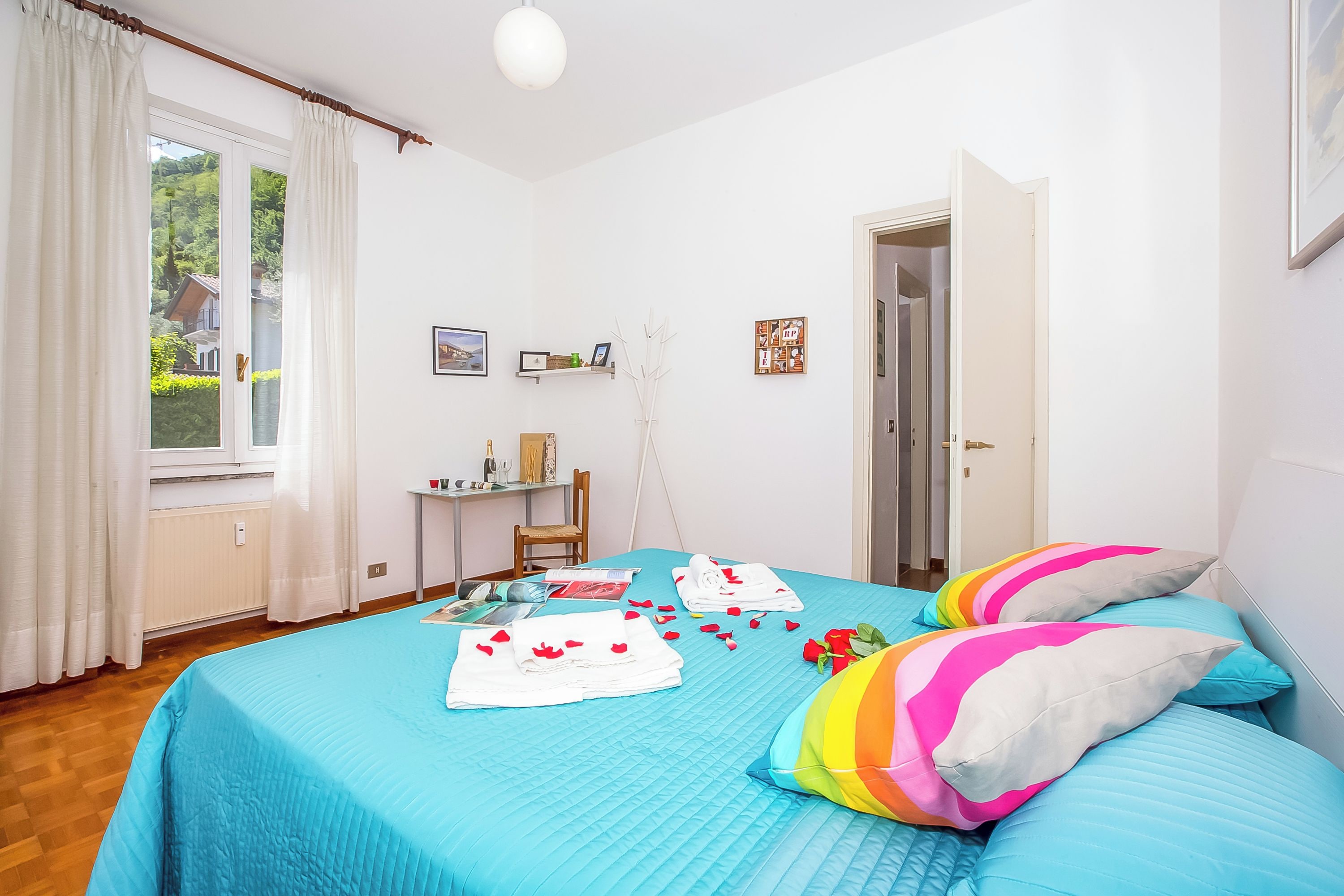 Ein Schlafzimmer mit Bett, Schreibtisch, Stuhl und einem Fenster mit Vorhängen.