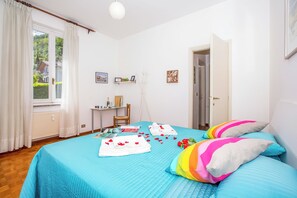 Un dormitorio con cama, escritorio, silla y ventana con cortinas.