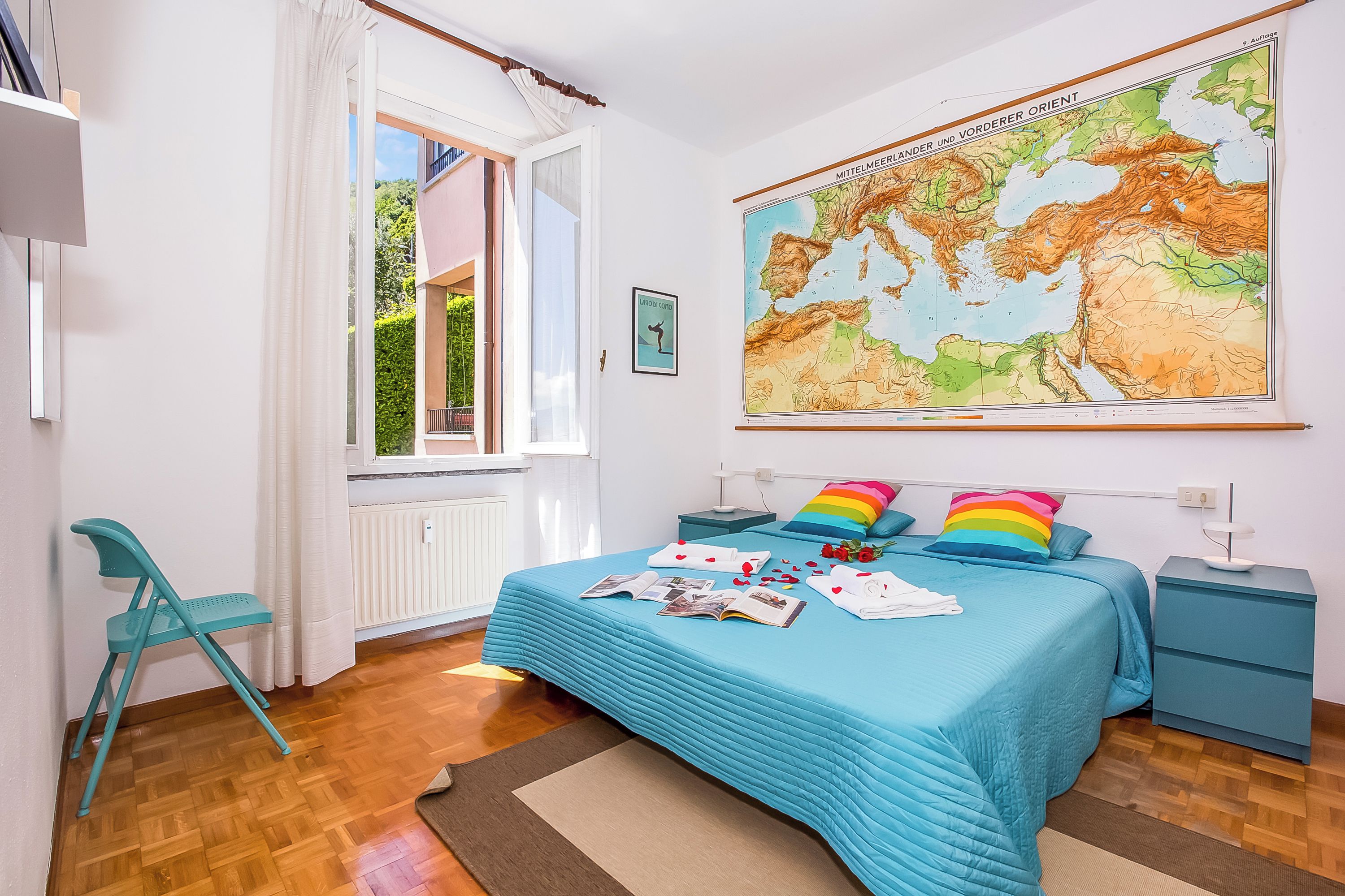 Ein Schlafzimmer mit einem Bett, einer Wandkarte, einem Sessel und einem Nachttisch.