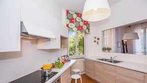 Une cuisine moderne équipée d’une cuisinière intégrée, d’un évier et d’une fenêtre agrémentée d’un rideau à motifs floraux.