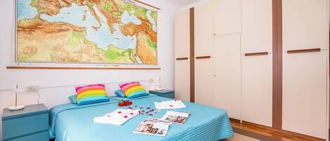 A bedroom with a large bed, a map on the wall, and a wardrobe.
