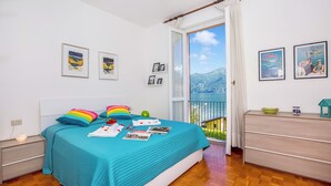 Une chambre à coucher comprenant un lit, une commode, une table de chevet, une fenêtre avec vue et des tableaux encadrés accrochés au mur.