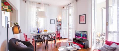 A modern living room with a dining area, a television, and a sofa.
