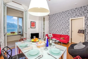Un comedor con una mesa preparada para cuatro personas, un sofá rojo y un sillón inflable negro.