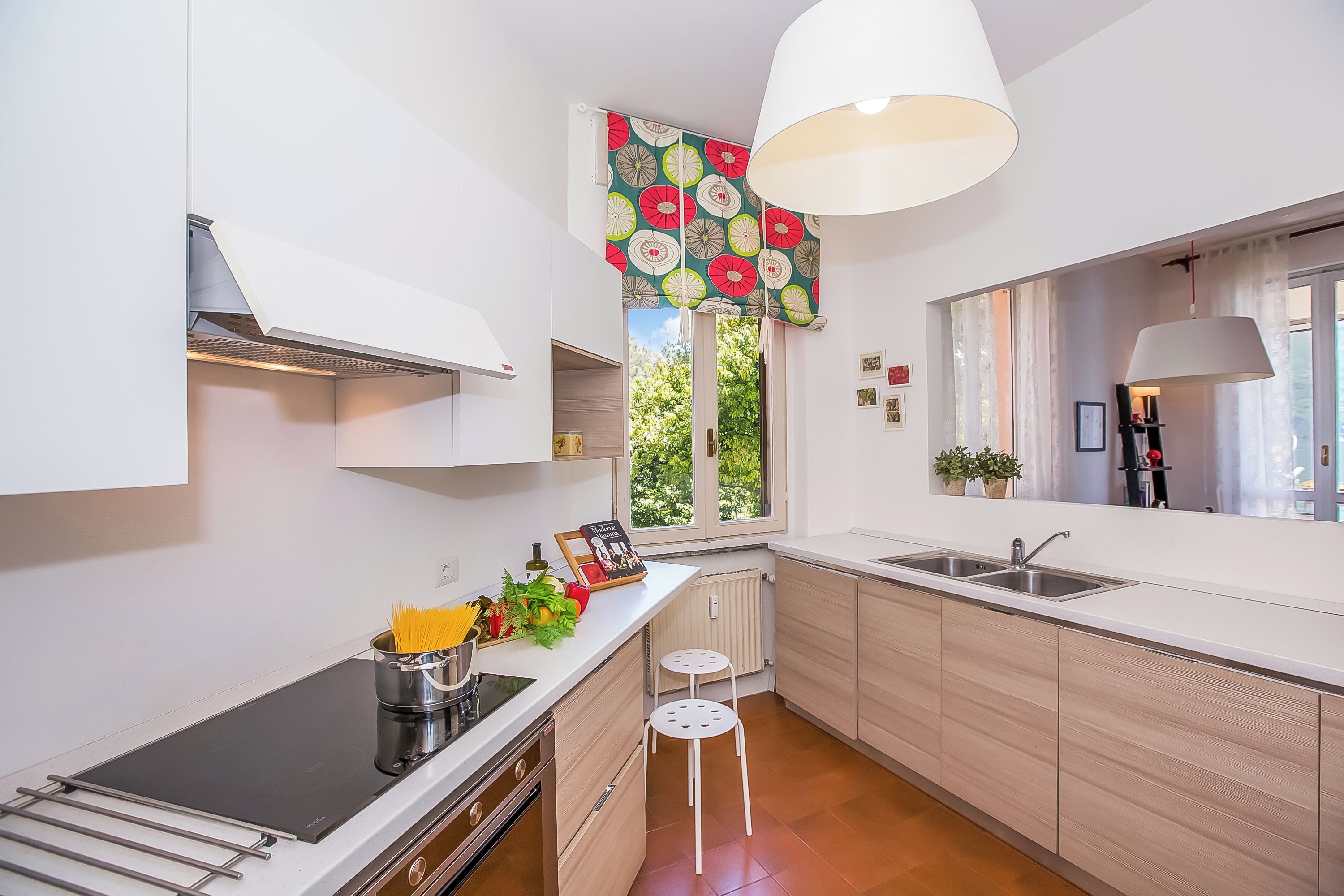 Eine moderne Küche mit Einbauherd, Spüle und einem Fenster mit floralem Vorhang.