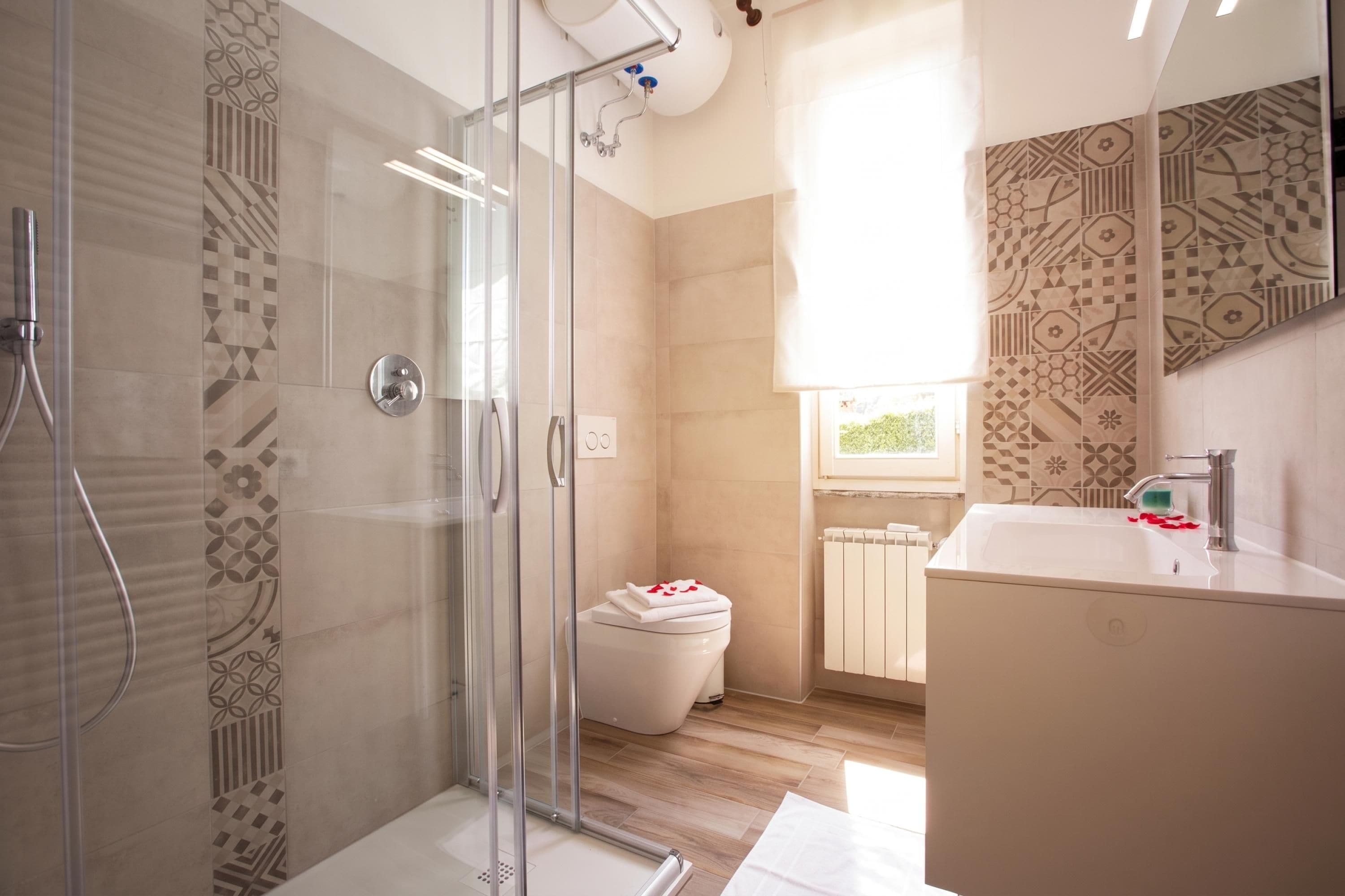 A modern bathroom with a glass shower enclosure, a toilet, and a sink with a mirror.