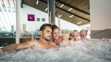 Relax in a serene hot tub surrounded by a contemporary spa setting with a high ceiling and natural light.