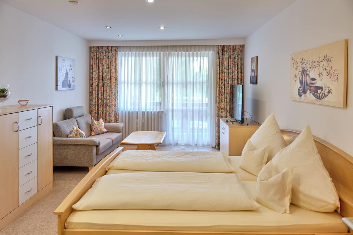 A hotel room with a bed, a sofa, a desk, and a TV.