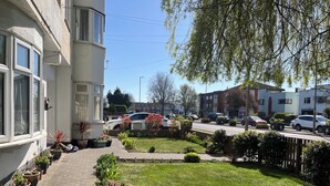 En bostadsgata med hus, en asfalterad gångväg och planterade blommor i krukor.