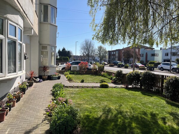 A residential street with houses, a paved walkway, and potted plants.