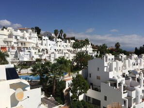 Una zona residencial costera con edificios blancos, palmeras y cielo despejado.