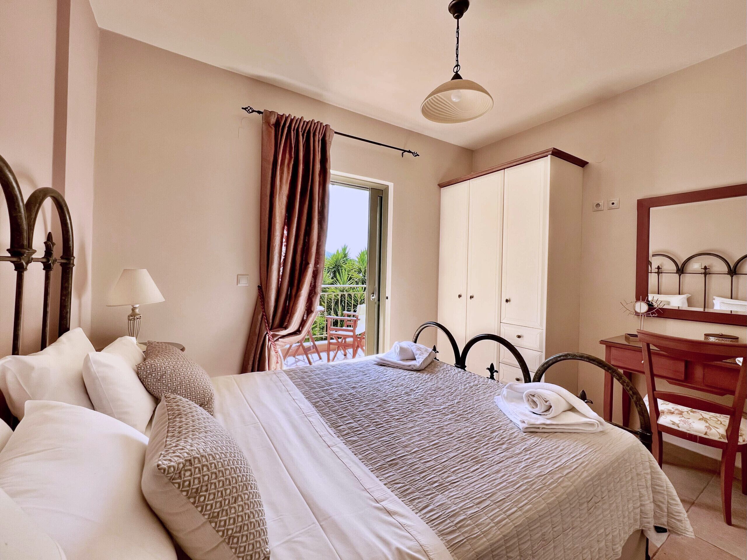 A bedroom with a bed, a desk, a chair, a wardrobe, and a balcony with a chair.