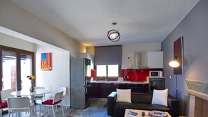 Una cocina moderna equipada con refrigerador, microondas y estufa. Hay un comedor con mesa y sillas, y una sala de estar con sofá y mesa de centro.