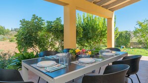 An outdoor dining area with a long table, chairs, and a pergola structure. - Country Home “Son Serra” in Rural Area with Air Conditioning, Terrace & Garden (Buger)